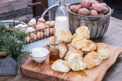 biscuits, jug of milk, baskets of potatoes and eggs