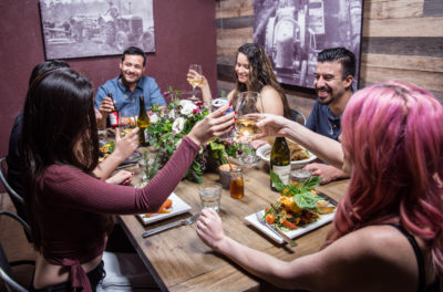 group eating around table and toasting with drinks